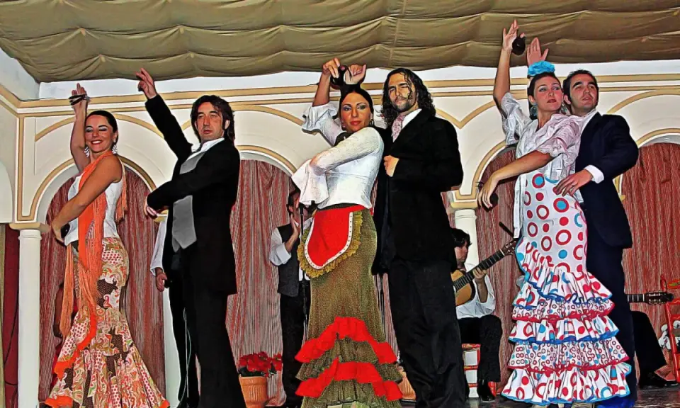 Artistas muestran cómo se bailan las sevillanas con pasión y gracia. Vestidos vibrantes y castañuelas llenan el escenario.