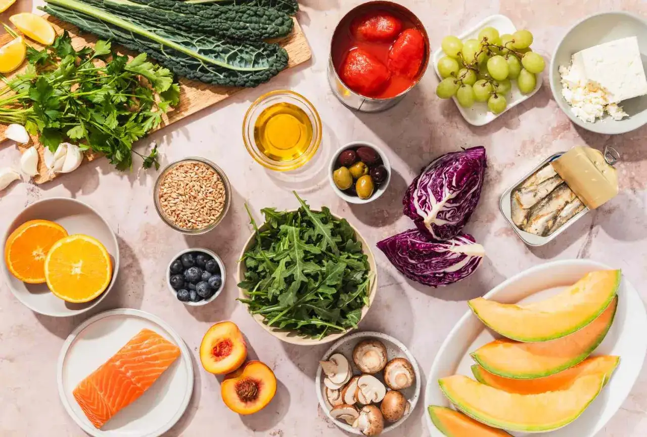 Ingredientes frescos para recetas saludables: salm&oacute;n, verduras de hoja verde, frutas, aceitunas, sardinas y m&aacute;s.