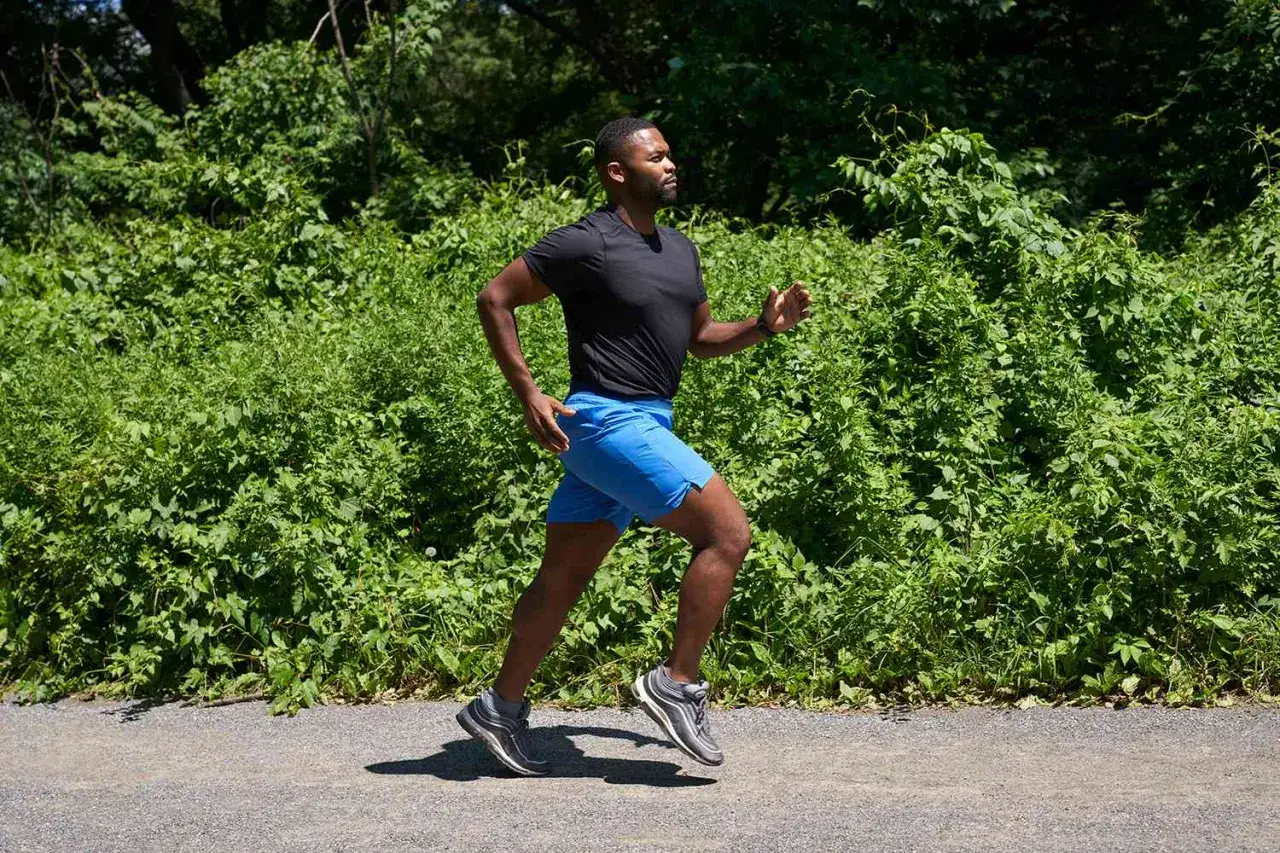 Hombre corre por un sendero rodeado de vegetaci&oacute;n exuberante.