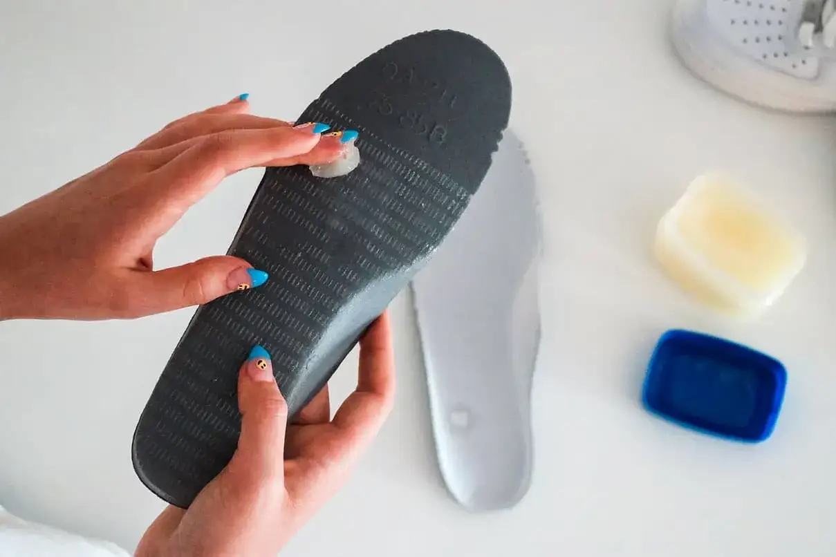 Manos aplicando vaselina en una plantilla para zapatos. Soluci&oacute;n para como quitar ruido zapatos goma.