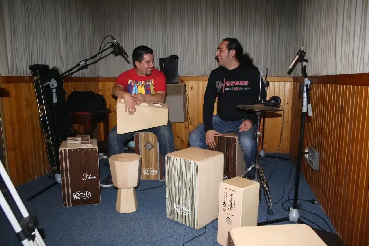 Dos hombres sentados en un estudio de m&uacute;sica, rodeados de varios cajones peruanos, listos para explorar las partes de un caj&oacute;n y crear ritmos.
