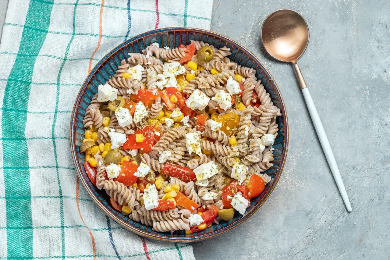 Ensalada de pasta fit con fusilli integral, tomate, ma&iacute;z, aceitunas y queso feta. Un plato ligero y sabroso.
