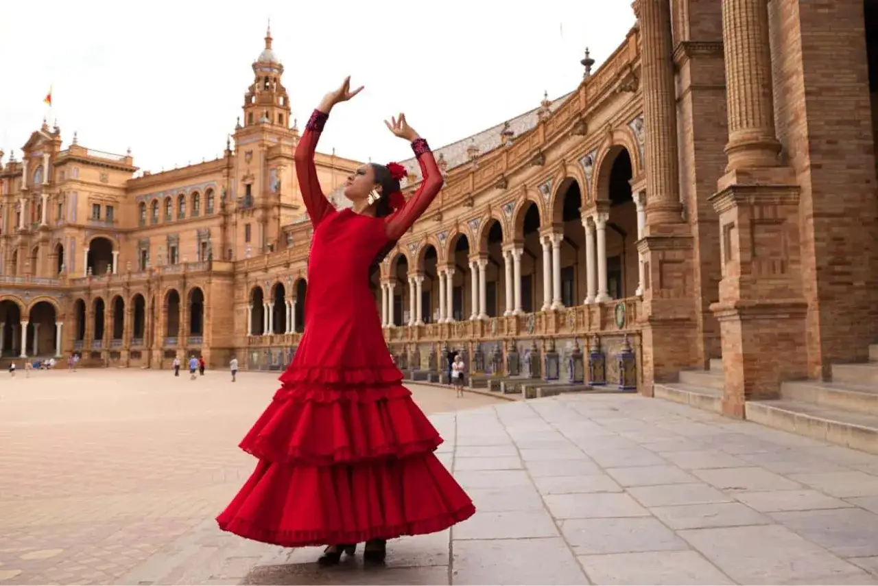 Una mujer con un vestido rojo voluminoso realiza un baile t&iacute;pico de Sevilla en la Plaza de Espa&ntilde;a.