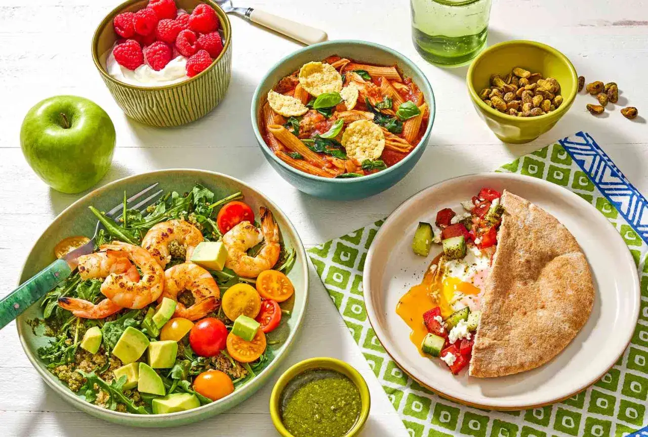Variedad de platos saludables: ensalada de gambas, pasta con tomate, desayuno con huevo y pan de pita, yogur con frambuesas y un vaso de agua. &iexcl;Perfecto para tus recetas fit!