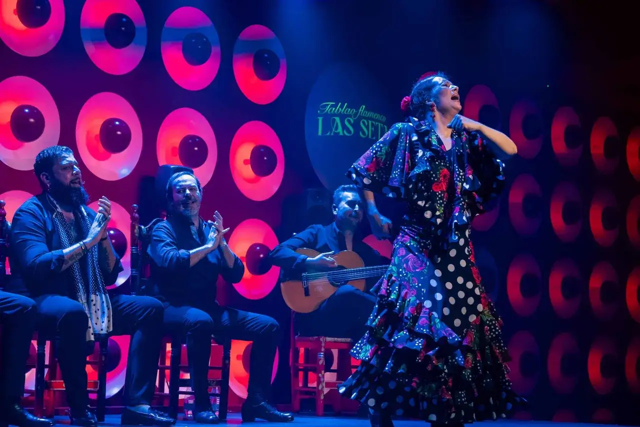 Una bailaora flamenca, con un vestido de lunares y flores, expresa pasi&oacute;n. A su lado, m&uacute;sicos acompa&ntilde;an con guitarra y palmas. El jaleo significado de esta escena es pura emoci&oacute;n.