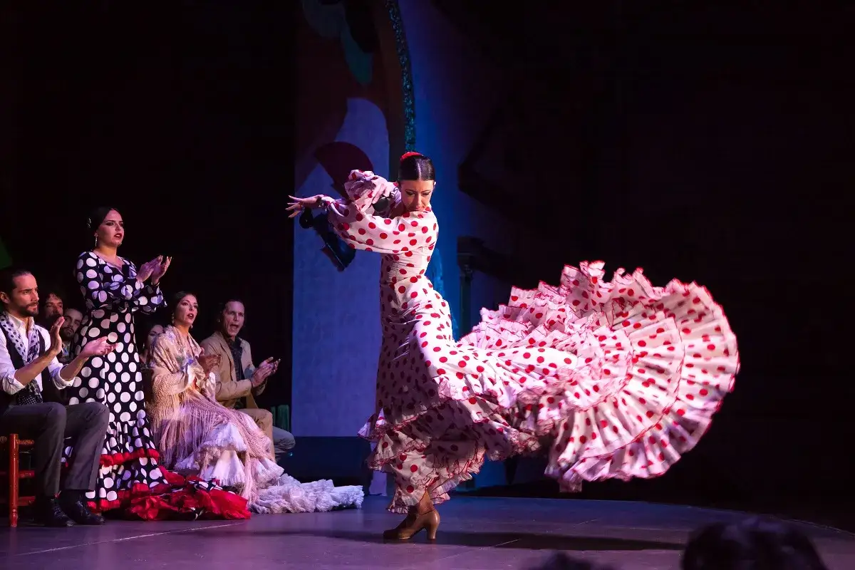 Bailaora de flamenco con un vestido de lunares rojos y blancos, su falda ondea con la energ&iacute;a de una seguiriya flamenca.