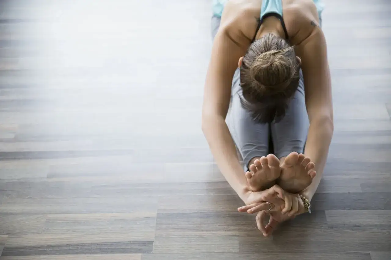 Mujer en postura de yoga, mostrando los diferentes tipos de flexibilidad en sus piernas y espalda.