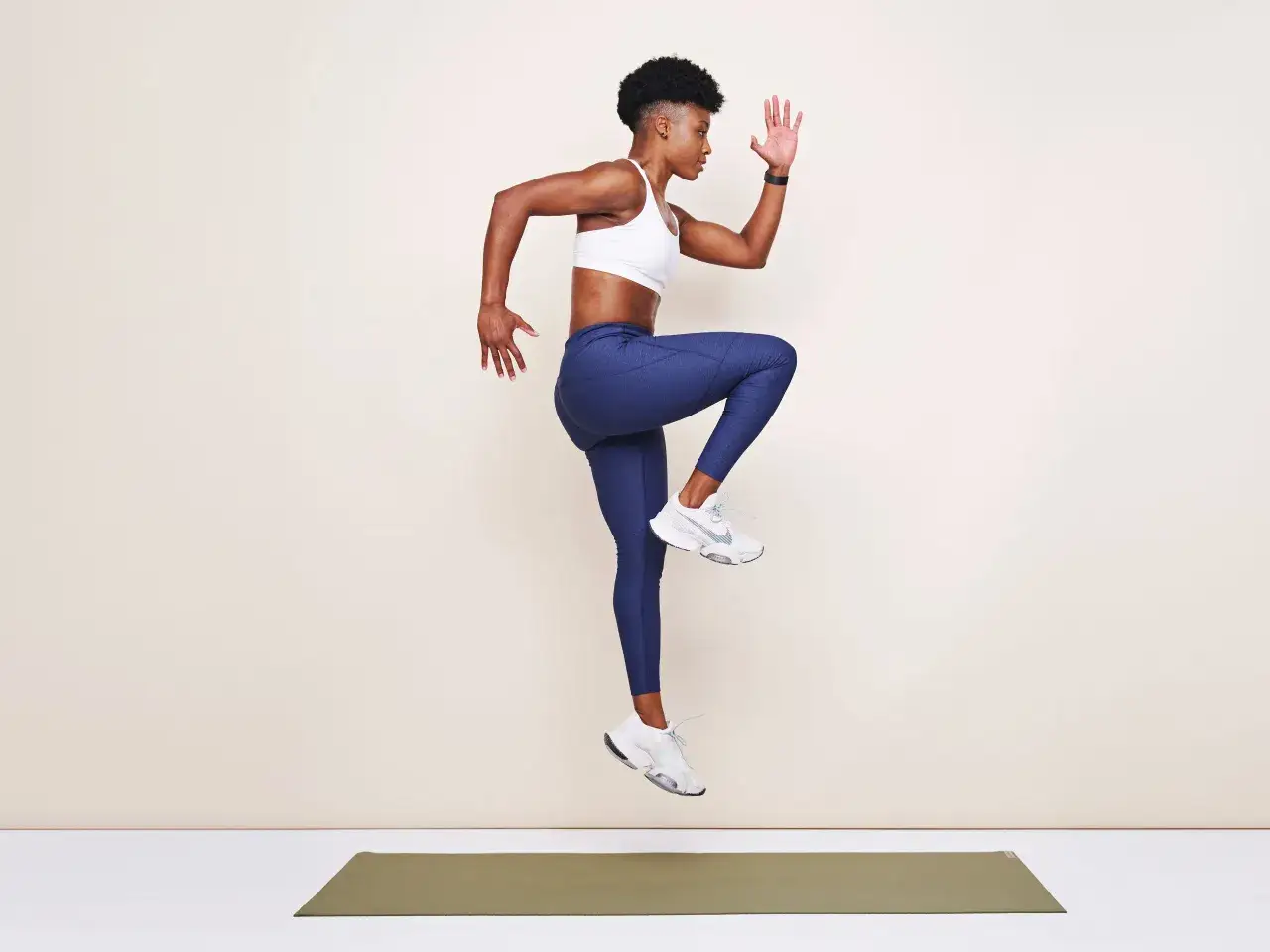 Mujer en el aire, rodilla levantada, demostrando para qué sirve la pliometría: potencia y agilidad.