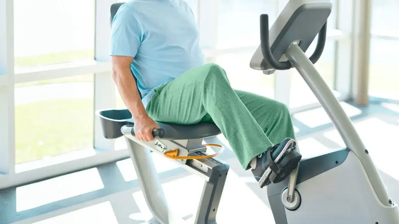 Hombre pedaleando en bicicleta estática. Es bueno hacer bicicleta para la artrosis de rodilla, alivia el dolor y mejora la movilidad.