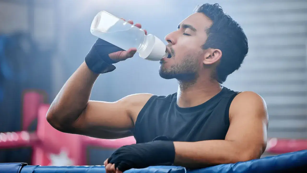 Boxeador bebe agua con electrolitos que son esenciales para su recuperaci&oacute;n tras el entrenamiento.