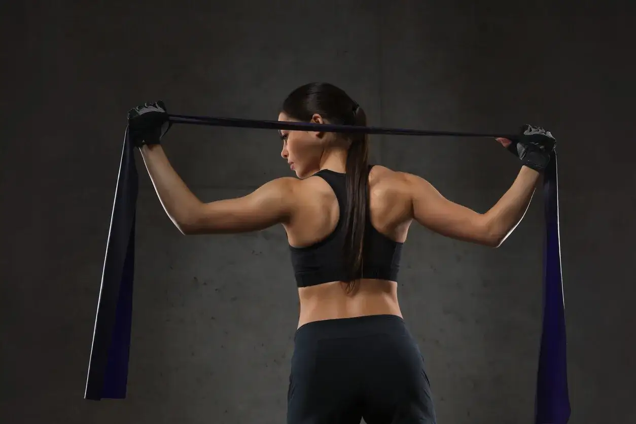 Mujer realizando ejercicios de pecho con gomas, enfocada en su entrenamiento.