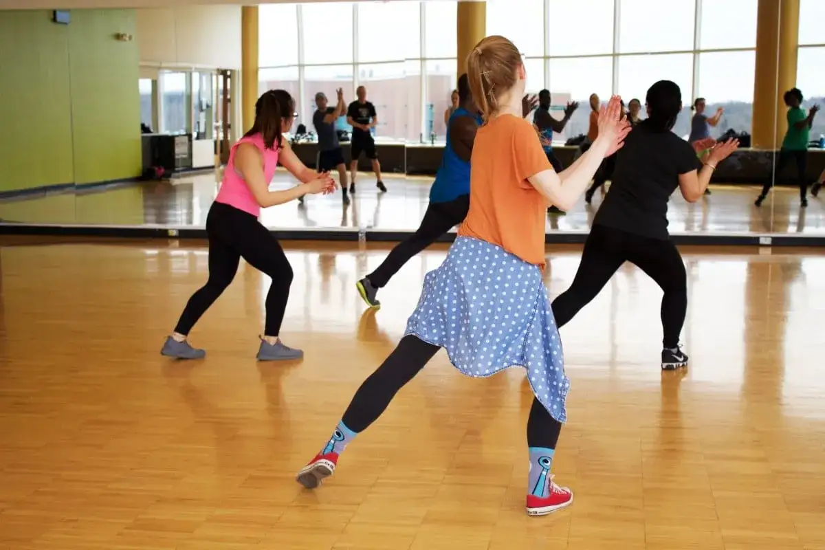 Personas disfrutando de los beneficios de bailar en una clase de ejercicio grupal.