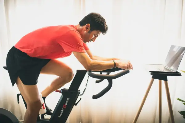 Hombre en bicicleta estática, entrenando para mejorar su artrosis de rodilla.