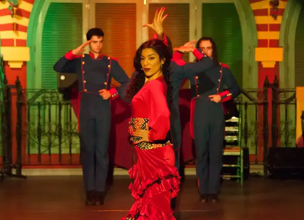 Una bailaora de flamenco con un vestido rojo vibrante, rodeada por dos hombres con uniformes militares, capturando la esencia de las alegrías flamenco.