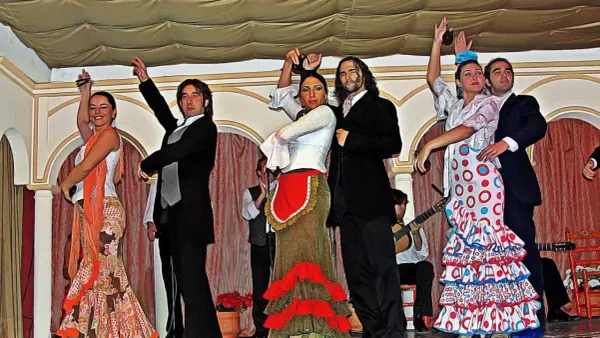 Artistas muestran cómo se bailan las sevillanas con pasión y gracia. Vestidos vibrantes y castañuelas llenan el escenario.