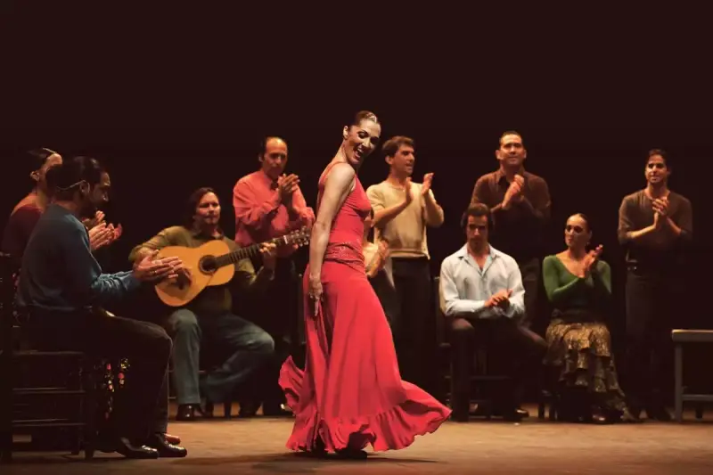 Bailaora flamenca en vestido rojo, acompañada por guitarrista y palmas. Un espectáculo de mejor flamenco.